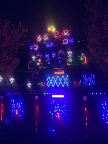 Halloween display with blue spiders on the fence and pumpkins on the house