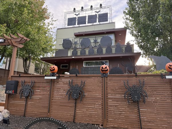 Spider props along the front fence with illuminated pumpkins above them