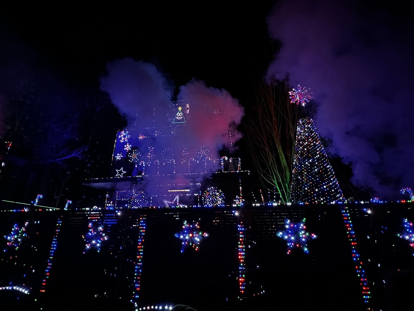 Fog drifting over the Christmas display with the mega tree lit in blue